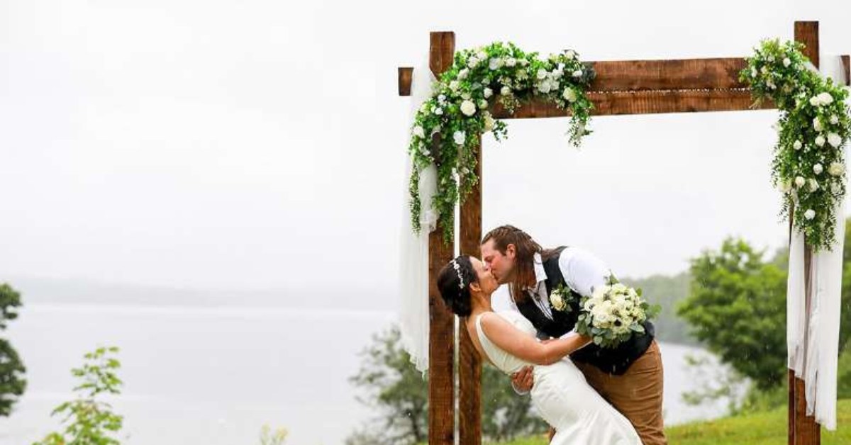 a wedded couple kissing in front of a wood archway