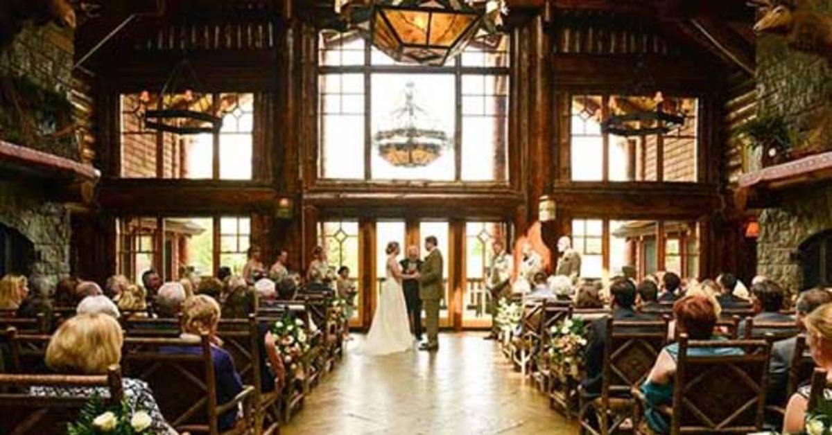 couple getting married in front of a large window in a rustic lodge