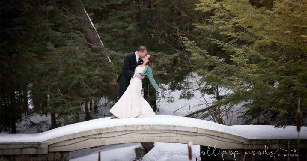 a couple poses for wedding pictures on a snow-covered bridge