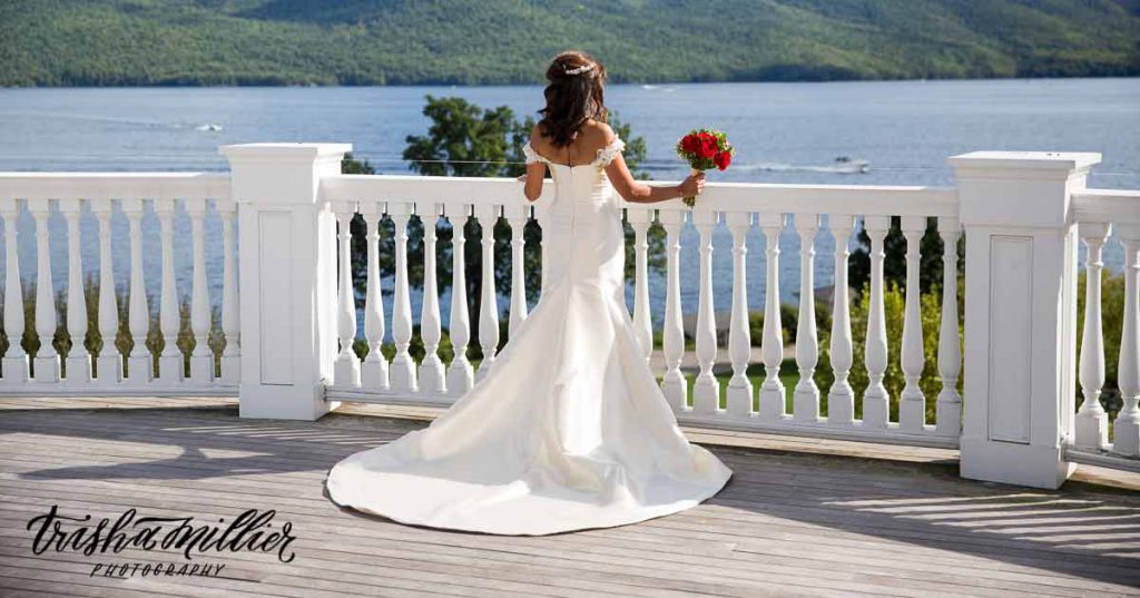 A bride looks out over Lake George from a balcony at The Sagamore.