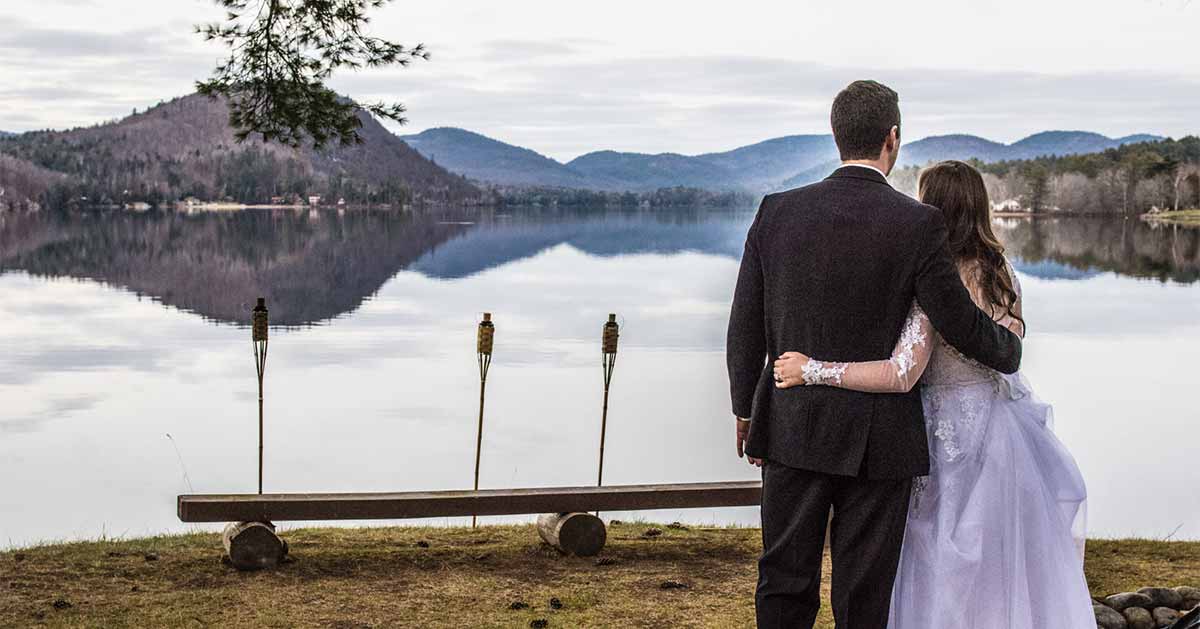 A couple stands with their back to the camera while looking out over Brant Lake.
