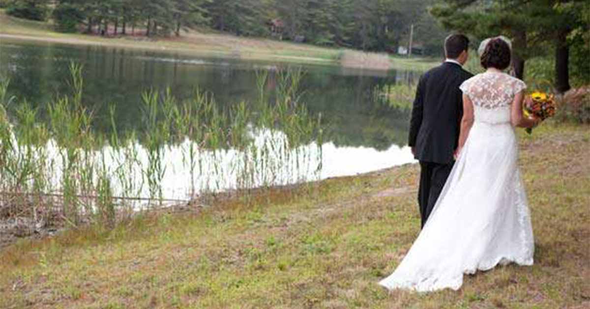 A bride and groom walk along the water at The Lodge on Echo Lake.