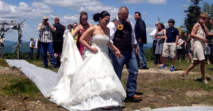 a bride and groom holding hands and being photographed at their mountaintop wedding