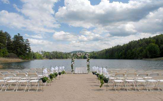 chairs set up for a wedding in front of a lake with an alter