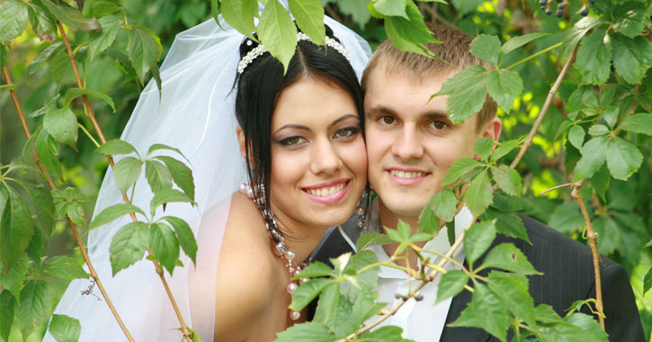 bride and groom posing among tree leaves
