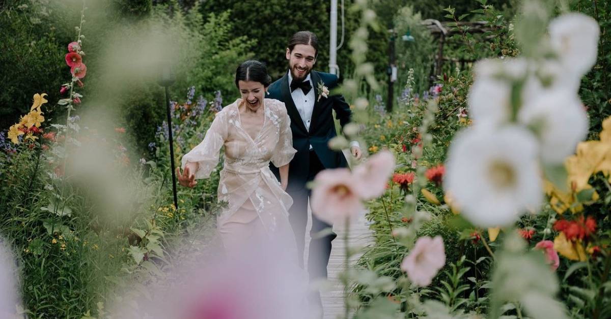 bride and groom runs laughing through garden
