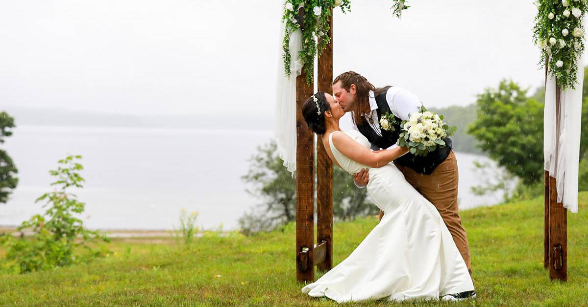bride and groom kiss under arch