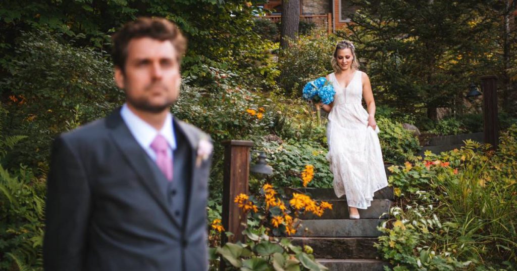 bride coming down garden steps in the background, blurred groom in foreground